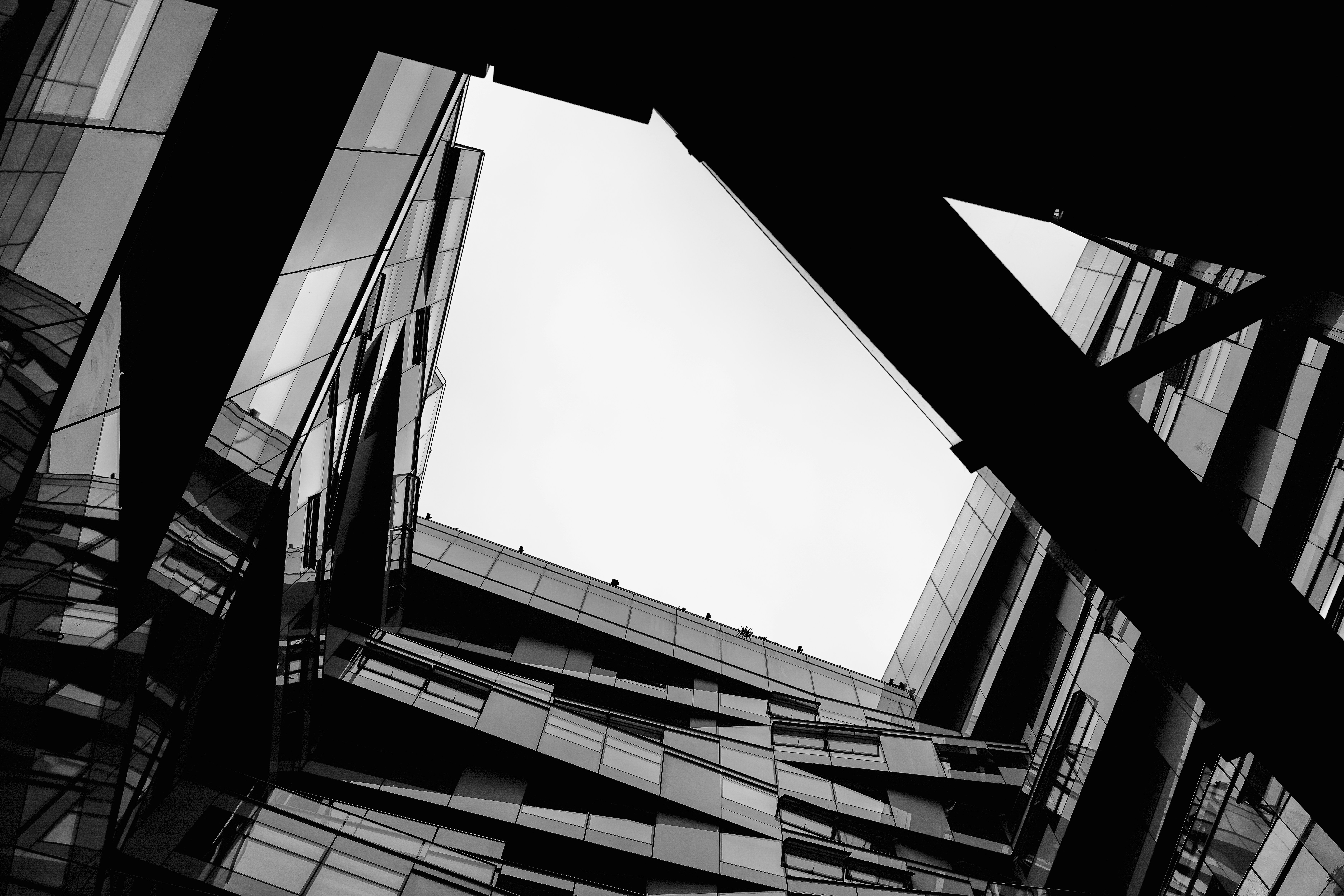 Black-and-white photograph looking up at angular glass architecture