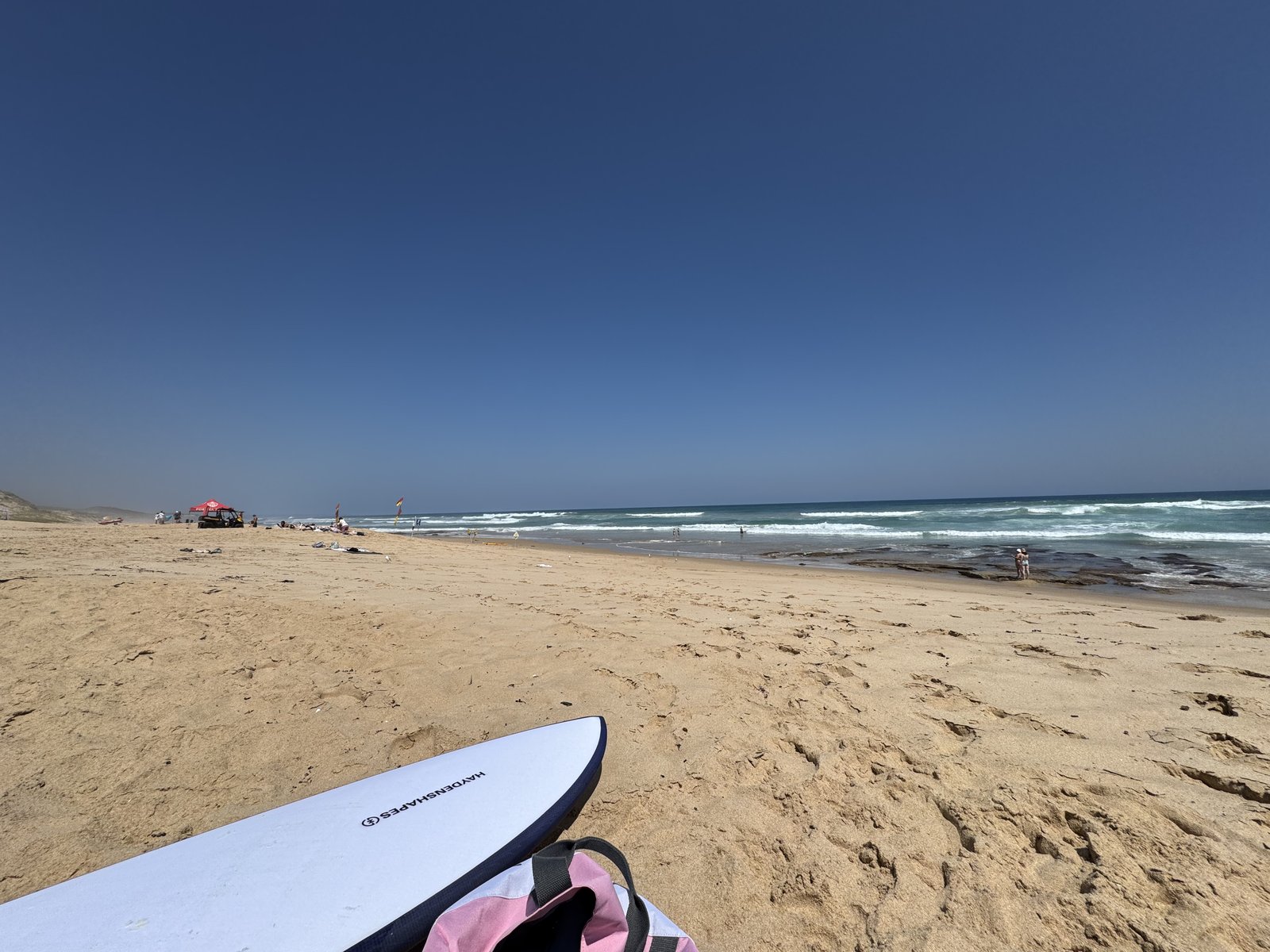 A surfboard on the sand at a bright, sunny beach