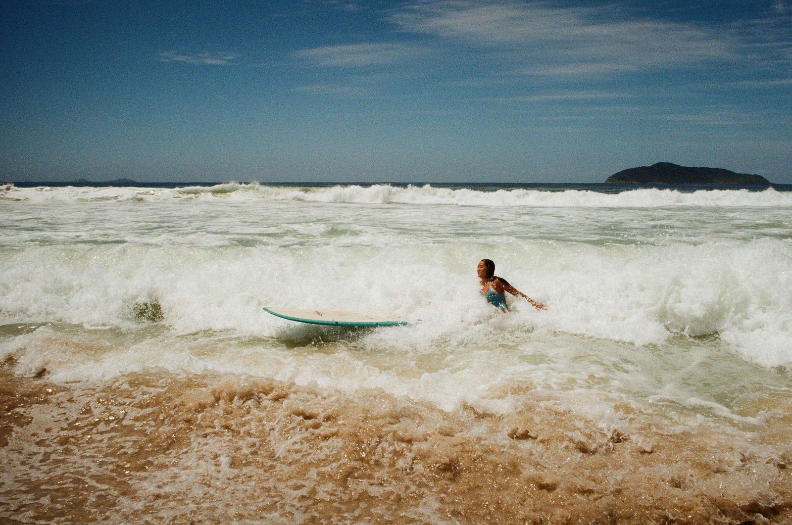 A surfer wading through the shore break at a Brazilian beach